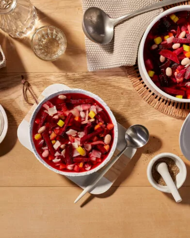 Stół z miskami barszczu ukraińskiego z mieszanką warzyw FRoSTA, śmietaną, bagietką, wodą i przyprawami.