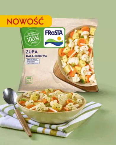 Miska zupą warzywną FRoSTA i opakowanie FRoSTA Zupa Kalafiorowa "Nowość" na zielonym tle, leżą na zielonej serwetce z łyżką.